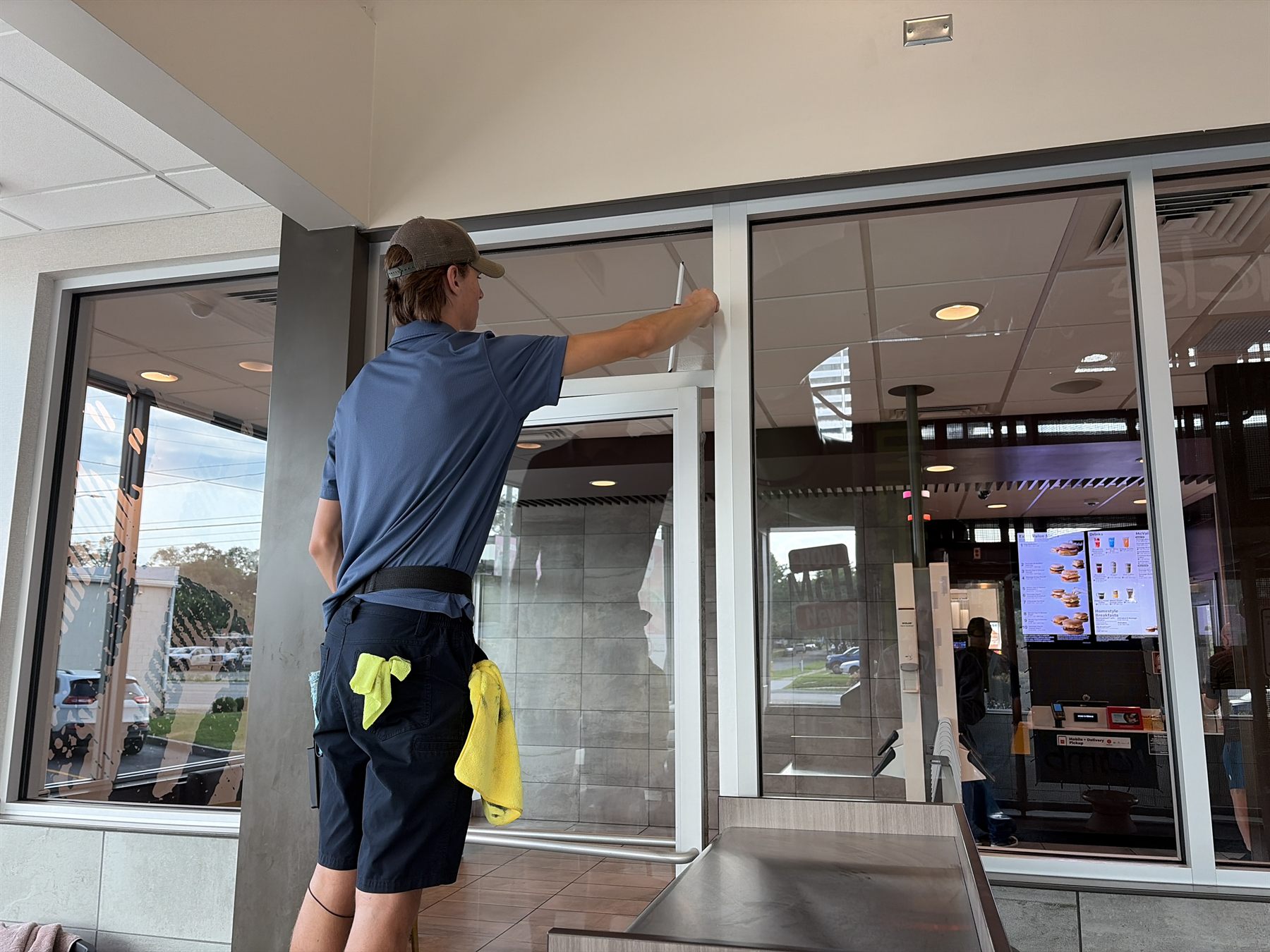 Team Gleam crew member squeegeeing storefront glass at a restaurant entrance