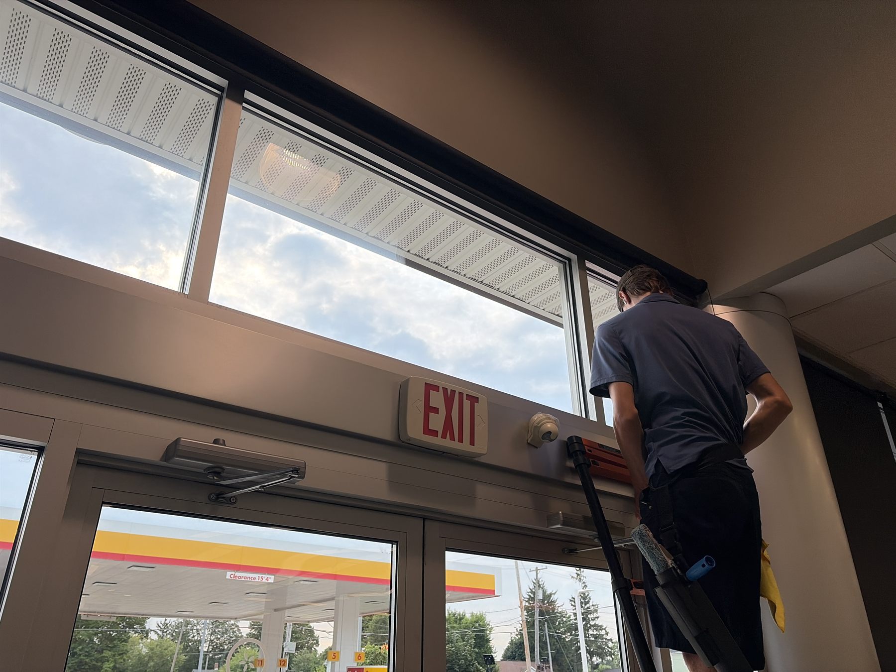 Cleaning transom windows above the entrance doors of a convenience store